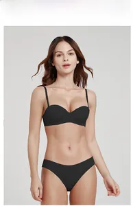Minimalist black seamless half-cup bra and panty set shown on a model against grey background