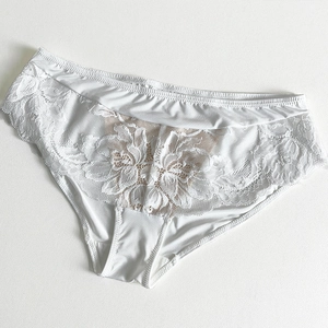Gros plan sur la dentelle florale blanche et la broderie de cette culotte sexy