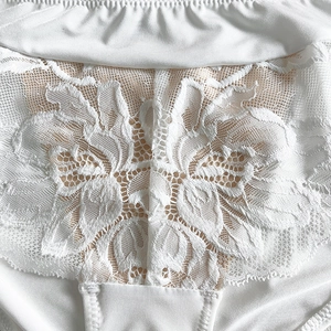 Détail macro de dentelle florale blanche élégante et de satin lisse sur la lingerie fine