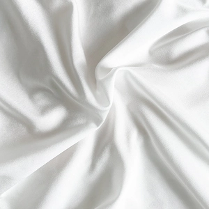 Détail de soie blanche montrant le drapé doux et l'éclat perlé de la culotte en dentelle