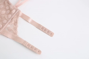Detail of light pink lace bra with four-row hook and eye back closure and polka dot mesh