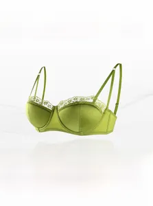 Detail of green satin bra with delicate white lace trim and adjustable thin straps