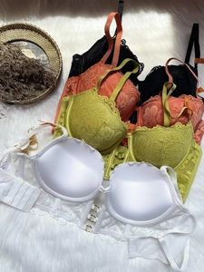 Gros plan de soutiens-gorge push-up en dentelle blanche, verte, orange et noire sur fourrure