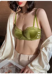 Detail of green satin bra with delicate lace trim and adjustable thin shoulder straps