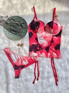 Detailed flat lay of floral lingerie set with corset and garter on plush white carpet