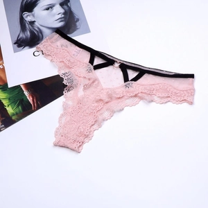 Détail d'un string en dentelle rose avec tulle à pois et boucle en métal doré en forme de cœur