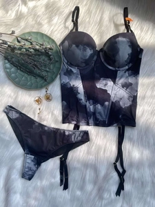 Flat lay of marble print corset lingerie set with garters on white plush background