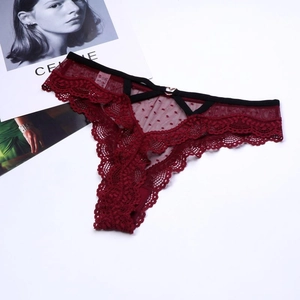 Détail d'un string en dentelle rouge avec tulle à pois et métal doré en forme de cœur