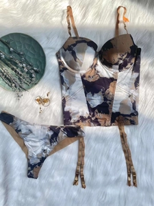 Flat lay of a three-piece floral corset lingerie set with garter belt on plush background