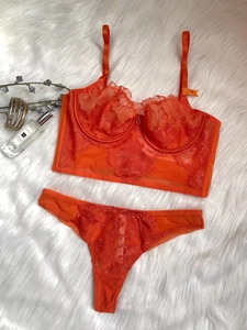Detailed flat lay of bright orange lace lingerie set with 75B size tag on fuzzy white rug