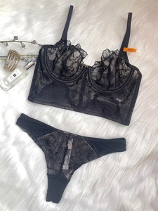 Detailed flat lay of black floral lace lingerie set with mesh fabric on soft white rug