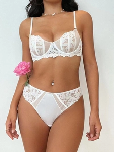 Detailed view of delicate white floral lace embroidery and silky satin on the bra and panty