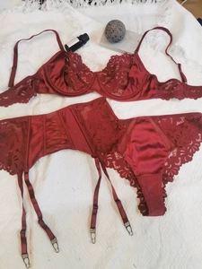 Flat lay of wine red lace lingerie set with bra, thong and garter belt detail