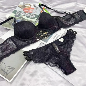 Detail of black lace bra and straps panty set with floral lace on silk background