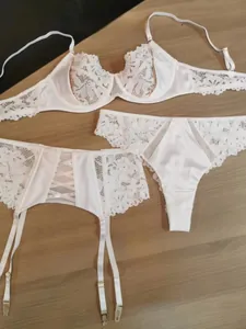 Detailed flat lay of a white lace 3-piece lingerie set with floral embroidery and garter belt