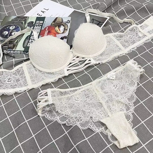 Flat lay of white floral lace lingerie set with bandage details and thin straps