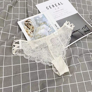 Detail of cream lace panties with cross-strap sides and a heart-shaped charm detail