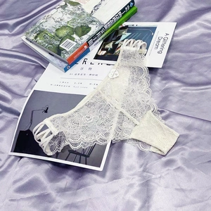 Close-up of white floral lace lingerie with elegant side strap detailing on silk background