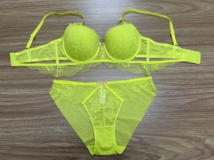 Flat lay of neon yellow lace lingerie set featuring floral cups and mesh side wings
