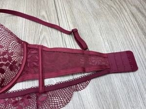 Macro detail of wine red floral lace bra featuring three-row hook and eye back closure