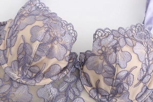 Detailed macro view of lavender lace bra with floral embroidery and satin bow decoration