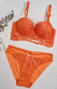Close-up of bright orange floral lace embroidery on push-up bra and panty set detail