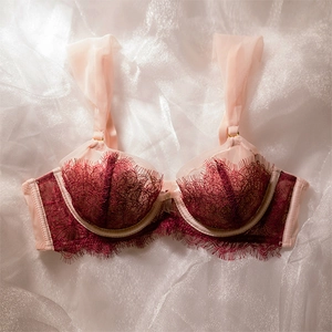 Detail of wine red floral lace cups and wide sheer mesh shoulder straps on a bra