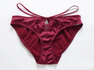 Détail de culotte en satin bordeaux avec dentelle de cils et nœuds à double sangle
