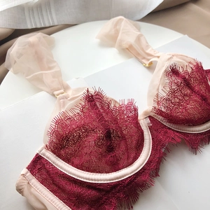 Close-up of burgundy eyelash lace and beige pleated mesh straps on a luxury wired bra