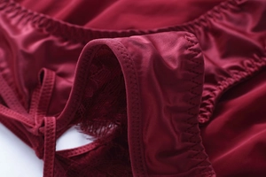 Détail du tissu lisse rouge vin avec dentelle de cils délicate et coutures en zigzag