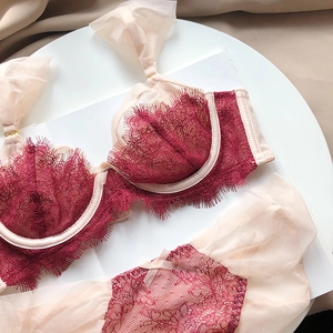 Flat lay of burgundy eyelash lace lingerie set with mesh ruffle details and bow