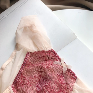 Detail of red floral lace panties with mesh sides and a tiny decorative bow accent