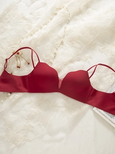Flat lay of seamless red push-up bra with elegant lace and pearl necklace background
