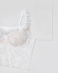 Gros plan d'un bustier en dentelle blanche avec bretelles à volants et texture florale fine