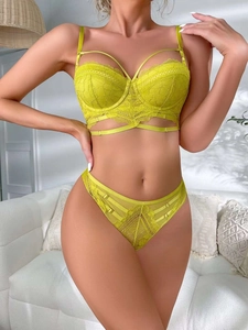 Detailed macro shot of yellow floral lace bra with cross straps and sheer hollow patterns