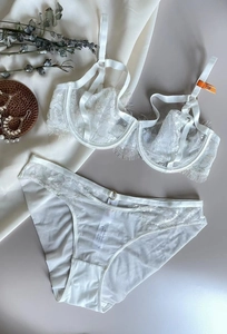 Close-up of white lace bra set with eyelash detailing and metal ring on silk panties