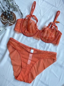 Flat lay of coral eyelash lace lingerie set with wired bra and sheer mesh panty detail
