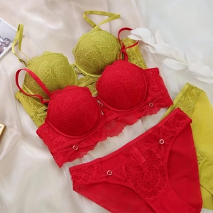 Détail à plat d'ensembles de lingerie en dentelle rouge et vert tilleul sur du satin