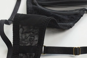 Close-up of black floral lace fabric with gold metal adjustment buckle on strap