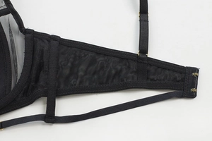 Detailed macro view of black lace bra mesh wings and gold metal adjustable strap buckles