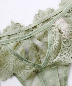 Détails d'une culotte en dentelle vert clair avec maille à pois et lanières croisées en V