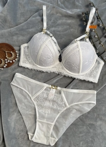 Détails d'un ensemble de lingerie en dentelle blanche avec broderies et anneaux dorés
