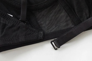 Detail view of black seamless bra featuring sheer mesh fabric and adjustable metal strap hooks