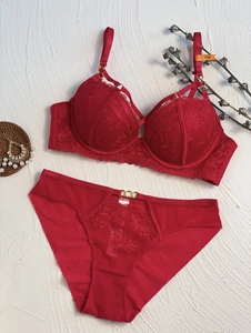 Détail à plat d'un ensemble de lingerie en dentelle rouge avec anneaux dorés et taille 75B