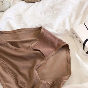 Détail d'une culotte sans couture marron à taille haute sur un tissu blanc texturé