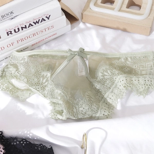 Detailed view of light green eyelash lace panties with a delicate bow on white bedding