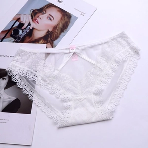 Close-up of white floral lace underwear with delicate bow and crisscross strap detail