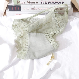 Close-up of light green lace panties with eyelash trim and mesh details on a bed