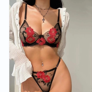 Détail d'un soutien-gorge en maille noire avec broderie florale rouge et texture délicate