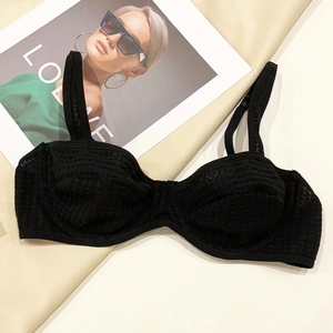 Detailed macro view of black textured semi-cup bra with polka dot pattern and wire support